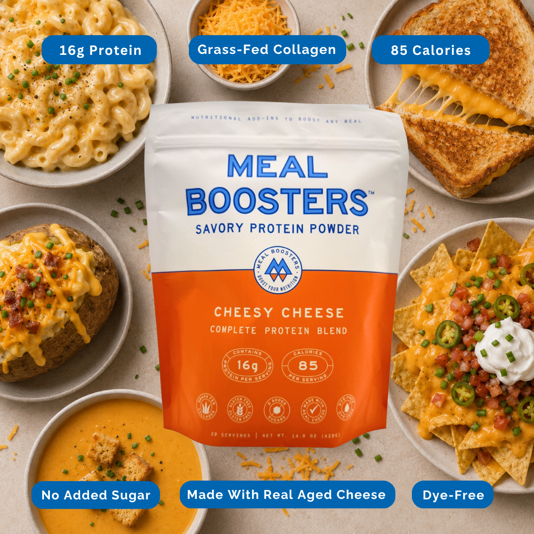 A bag of Meal Boosters Savory Protein Powder in Cheesy Cheese flavor is centered, surrounded by plated prepared foods including macaroni, grilled cheese, baked potato, soup, and nachos. Blue callout labels highlight key features: 16g Protein, Grass-Fed Collagen, 85 Calories, No Added Sugar, Made With Real Aged Cheese, and Dye-Free.