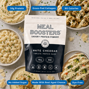 A stand-up pouch of Meal Boosters Savory Protein Powder in White Cheddar flavor is centered on a styled flat-lay of cheese dishes. Blue callout badges around the product read 16g Protein, Grass-Fed Collagen, 90 Calories, No Added Sugar, Made With Real Aged Cheese, and Dye-Free.