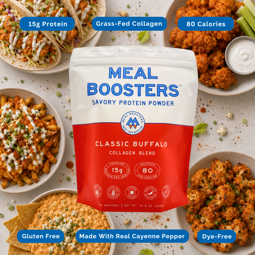 A bag of Meal Boosters Classic Buffalo Collagen Blend protein powder is centered on a styled flat-lay background showing prepared foods like tacos, wings, and pasta. Blue callout badges around the package highlight product features: 15g protein, grass-fed collagen, 80 calories, gluten free, made with real cayenne pepper, and dye-free.